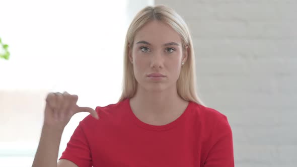 Young Blonde Woman showing Thumbs Down Gesture