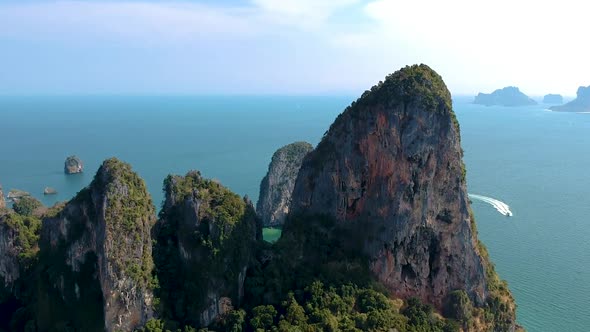 Aerial pan over large limestone karst with boat in the distance. Railay Beach, Ao Nang, Krabi, Thail