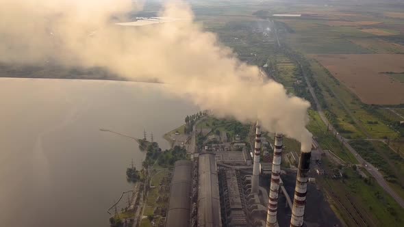 Aerial view of high chimney pipes with grey smoke from coal power plant. Production of electricity