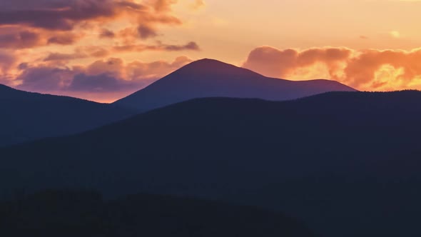 Beautiful Evening Panoramic Landscape with Bright Setting Sun Over Distant Mountain Peaks at Sunset
