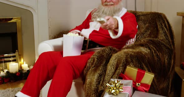 Santa claus eating popcorn while watching television