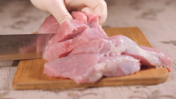 Metal Knife Cuts Up the Meat. Cutting Meat on a Wooden Board. Pork Is on the Board. Sliced Pork Meat