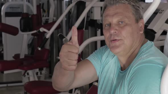 Senior Man with Thumb Up and Smile Between Exercises in Gym
