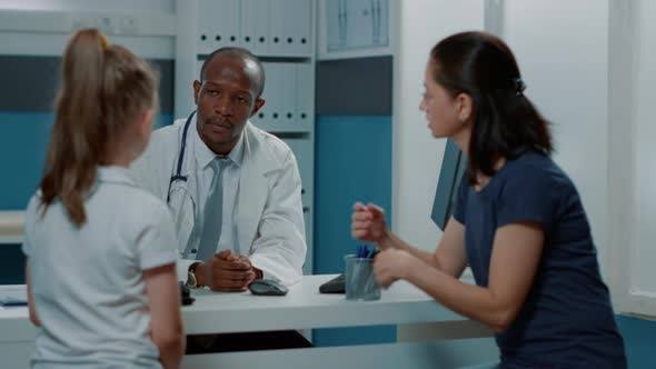 Male Doctor Talking to Little Child About Diagnosis and Treatment