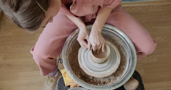 Female Potter Sitting and Makes a Cup on the Pottery Wheel. Woman Making Ceramic Item. Pottery