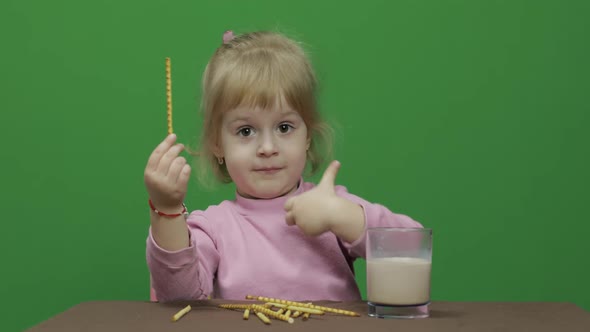 The Child Eats Cookies. A Little Girl Is Eating Cookies Sitting on the Table.