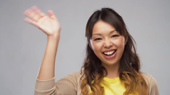 Smiling Asian Woman Waving Hand