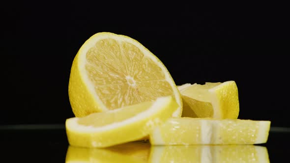 Closeup of Rotating Ripe Lemon Pieces on Black Background Making a Cocktail of Citrus Fruits