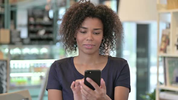 Portrait of Young African Woman Celebrating on Smartphone