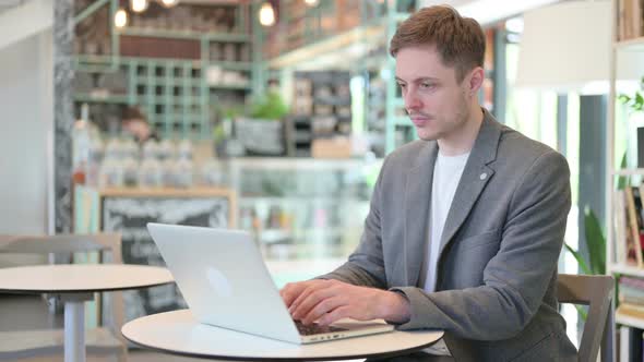 Young Man Working on Laptop in Cafe