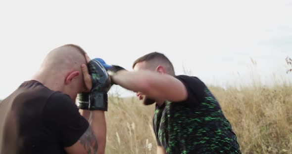 Two Sportsmen in Sportswear Training Free Fight Among Wild Grass on Sunset