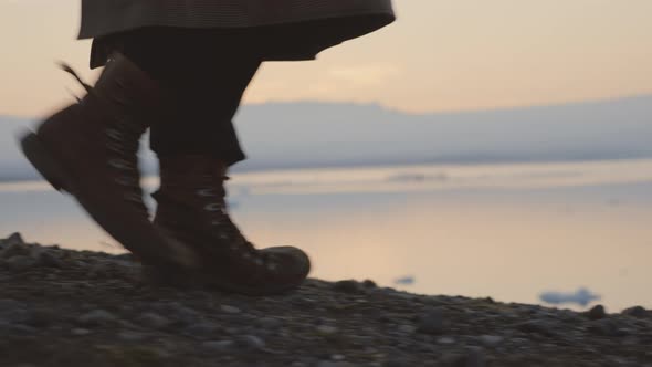 Man In Boots Walking Through Icelandic Landscape At Sunset