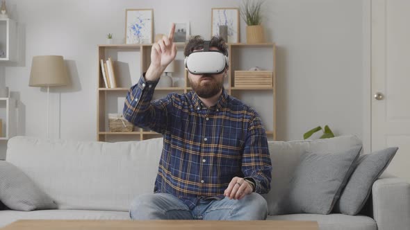 Young Caucasian Man in Virtual Reality Glasses Controls the Game with His Hands