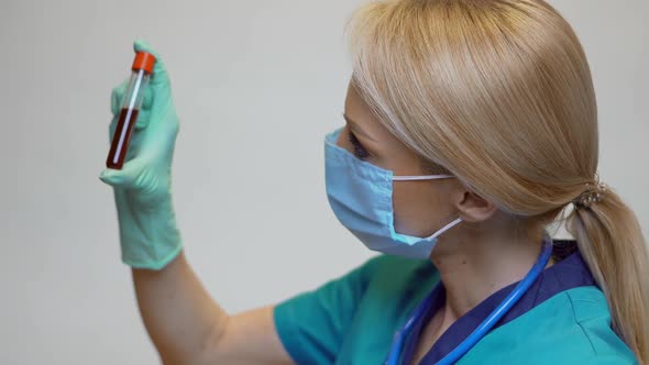 Medical Doctor Nurse Woman Wearing Protective Mask and Latex Gloves - Holding Blood Test Tube