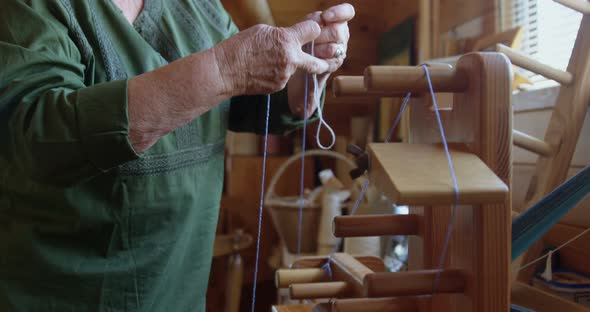Senior woman placing woollen thread on weaving machine 4k