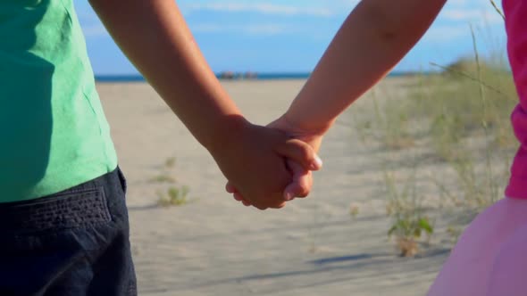 Closeup of Little Boy and Girl in Pink Skirt Holding Hands on the Beach