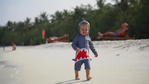 A Little Toddler in a Shark Costume Runs Towards the Camera and Laughs