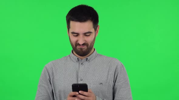 Portrait of Brunette Guy Is Texting on His Phone. Green Screen