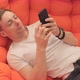 Man Looking at Photos on the Phone While Lying on the Couch - VideoHive Item for Sale