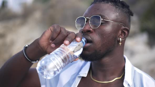 Headshot Portrait of Handsome Young African American Man in Sunglasses Drinking Refreshing Water on
