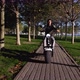 Male on electric scooter is riding through public park at sunny morning - VideoHive Item for Sale