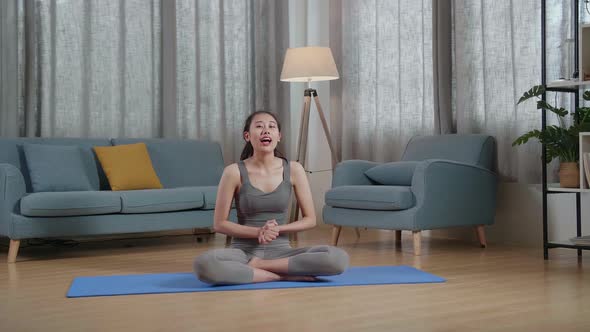 Asian Trainer Female In Sports Clothes Waving Hand And Speaking While Teaching Exercise At Home