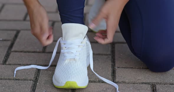 Young adult female tying shoe lace before a run