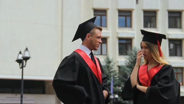 Young Woman and Man in Mantles and Caps Discussing Future, Graduation Day