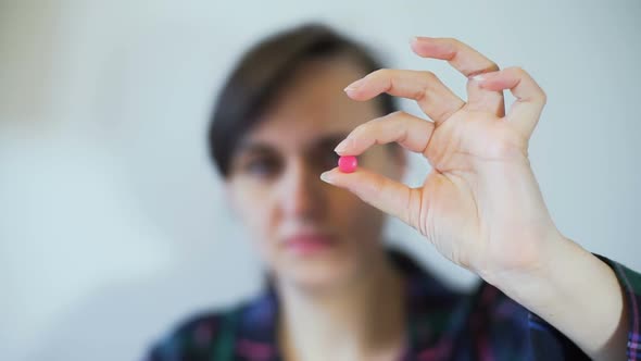 Woman Holding Pill in Hand and Looking at It