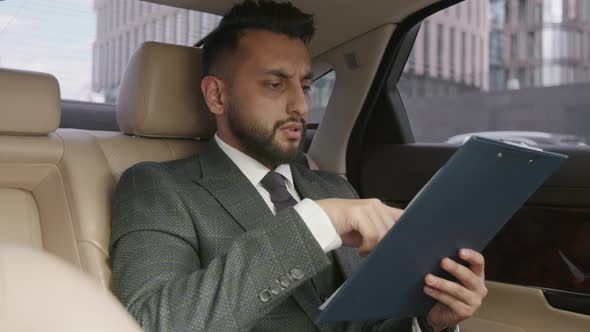 Businessman Going Through Documents in Car