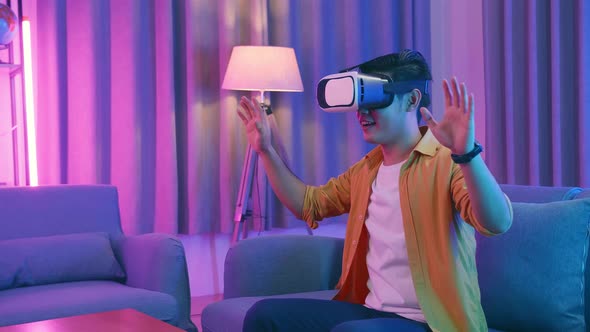 Young Asian Man Wearing Vr Headset At Living Room And Using Hand Slide , Cyan And Magenta Colors
