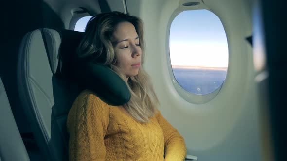 A Woman Is Relaxing While Trying To Sleep on the Airplane