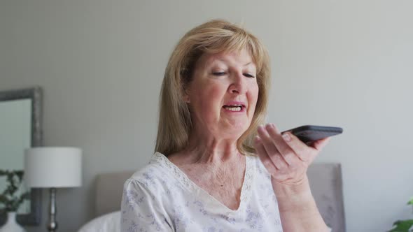 Senior woman talking on smartphone at home