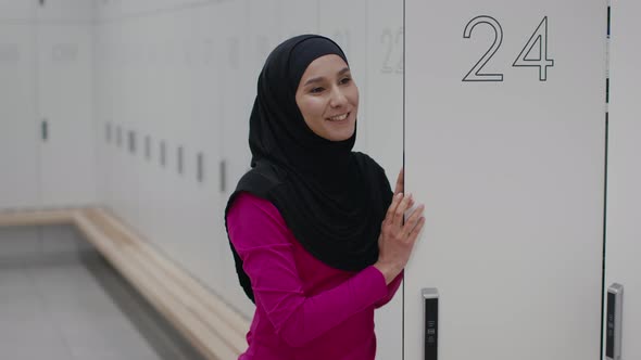 Young Middle Eastern Woman Wearing Hijab Talking with Interlocutor Standing at Modern Locker Room at