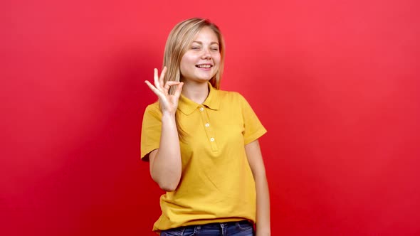 Beautiful Caucasian Woman in Yellow T-shirt and Long Blond Hair, Standing on Red Background