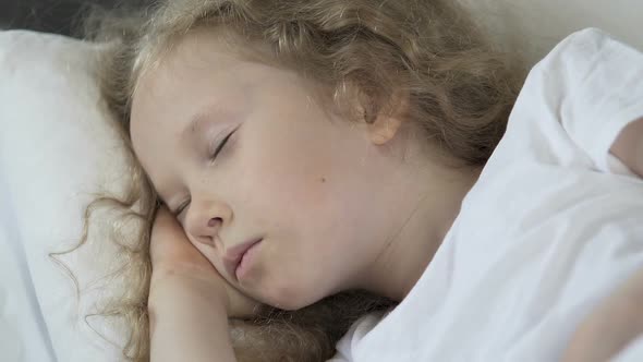 Beautiful Curly Hair Blond Child Sleeping in Her Bed