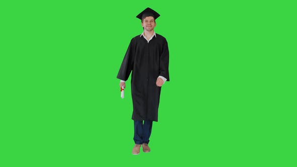 Smiling Male Student in Graduation Robe Walking with His Diploma on a Green Screen, Chroma Key