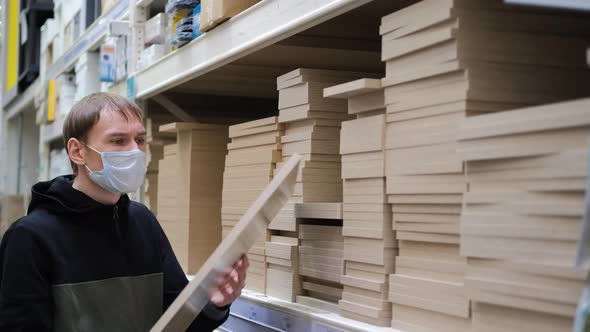 Man Choosing Wooden Plank in a Hardware Store