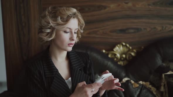 Lady Sitting on Luxury Sofa Typing on Smartphone and Looking Aside