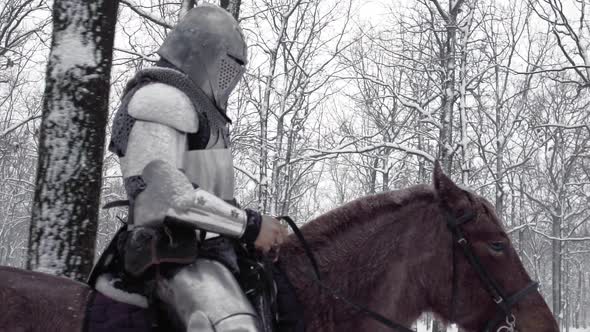 Strong Lone Gladiator Armed with Steel Weapon Riding on Dark Horse Through Winter Forest Under