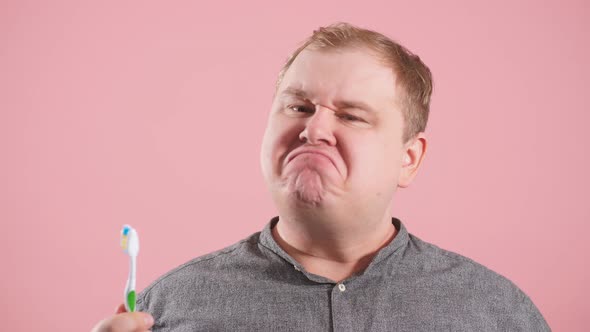 Pleasant Cheerful Man Brushing His Teeth with Vivid Emotions on Pink Background