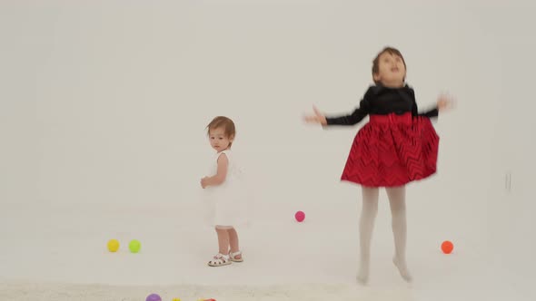 Toddler Girl Wearing Diaper and Her Sister Playing with Balls