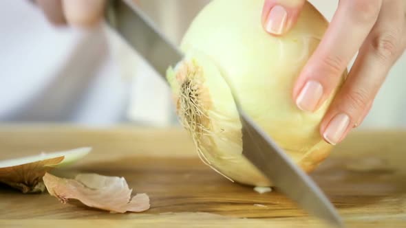 Step by step. Slicing yellow onion with kitchen knife on a cutting board.