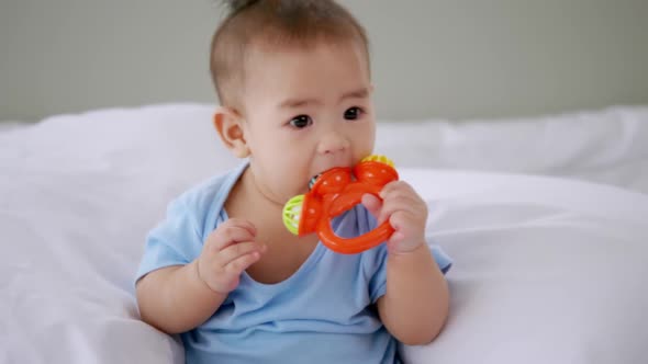 Adorable little baby playing a toy on bed.