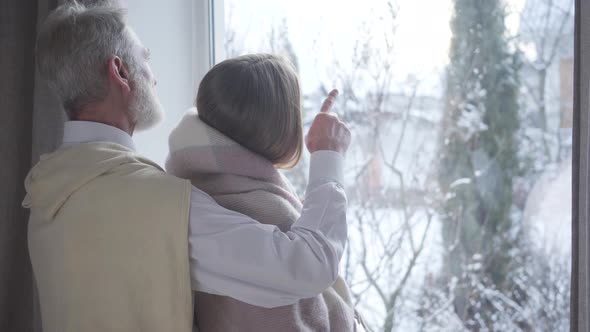 Confident Middle-aged Caucasian Man Pointing Out the Window and Talking To Young Woman. Happy Male