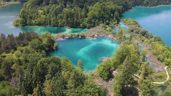 Top view of the Plitvice Lakes National Park with many green plants and beautiful lakes, walking pat
