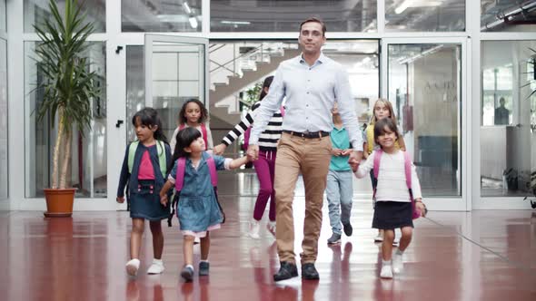 Smiling Male Teacher with Group of Children Going to Class