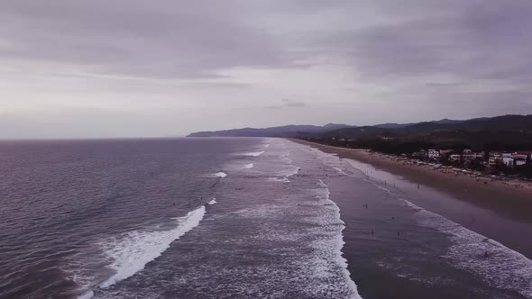 People At The Wavy Beach In Olon, Ecuador On A Cloudy Day - aerial drone