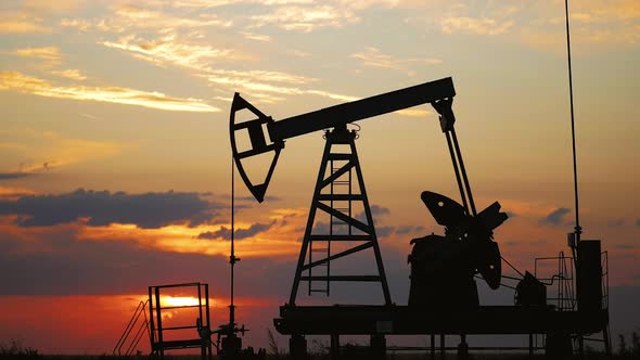 Silhouette Working Oil Pump in Deserted District at Sunset