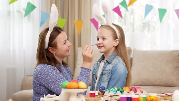 Mother Draws a Rabbit with Paints on Her Daughter's Face to Celebrate Easter